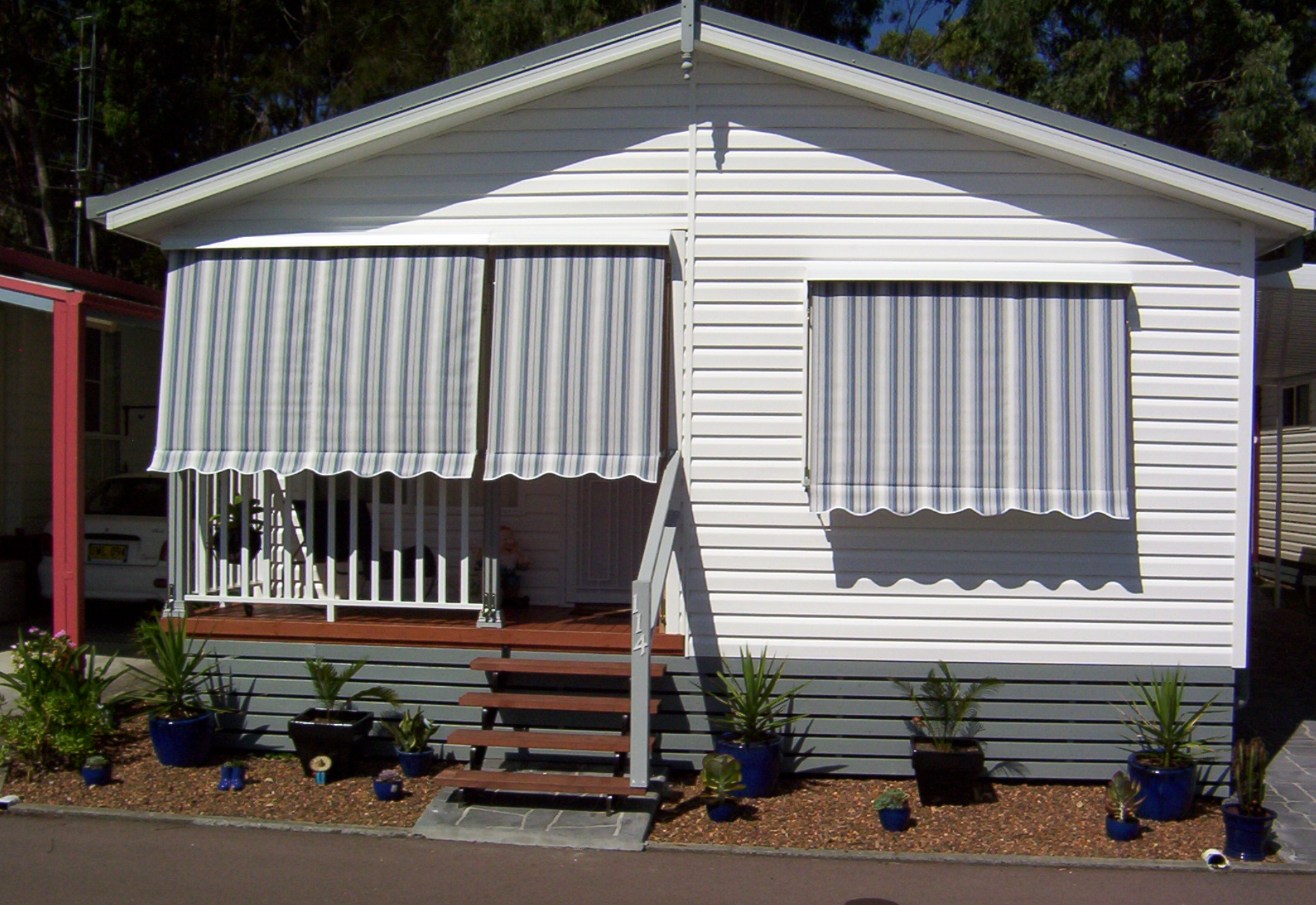 A Bamboo Building With A Green Awning On Top Of It — Mid Coast Flooring & Blinds In Laurieton, NSW