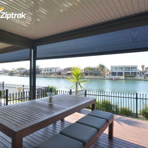 A Patio With A Table And Benches Overlooking A Body Of Water — Mid Coast Flooring & Blinds In Taree, NSW