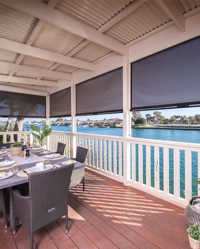 A Patio With A Table And Chairs Overlooking A Body Of Water — Mid Coast Flooring & Blinds In Old Bar, NSW