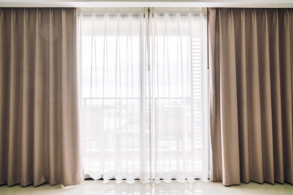 A Living Room With A Sliding Glass Door And Curtains — Mid Coast Flooring & Blinds In Wingham, NSW