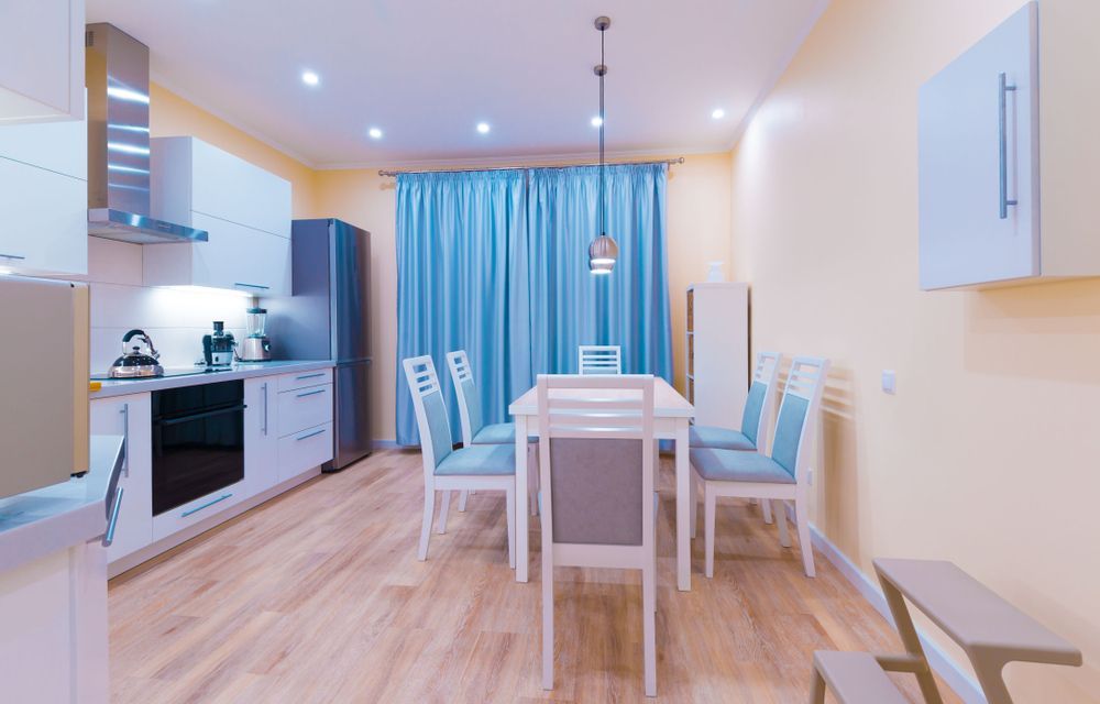 A Kitchen With A Table And Chairs And Blue Curtains — Mid Coast Flooring & Blinds In Wingham, NSW