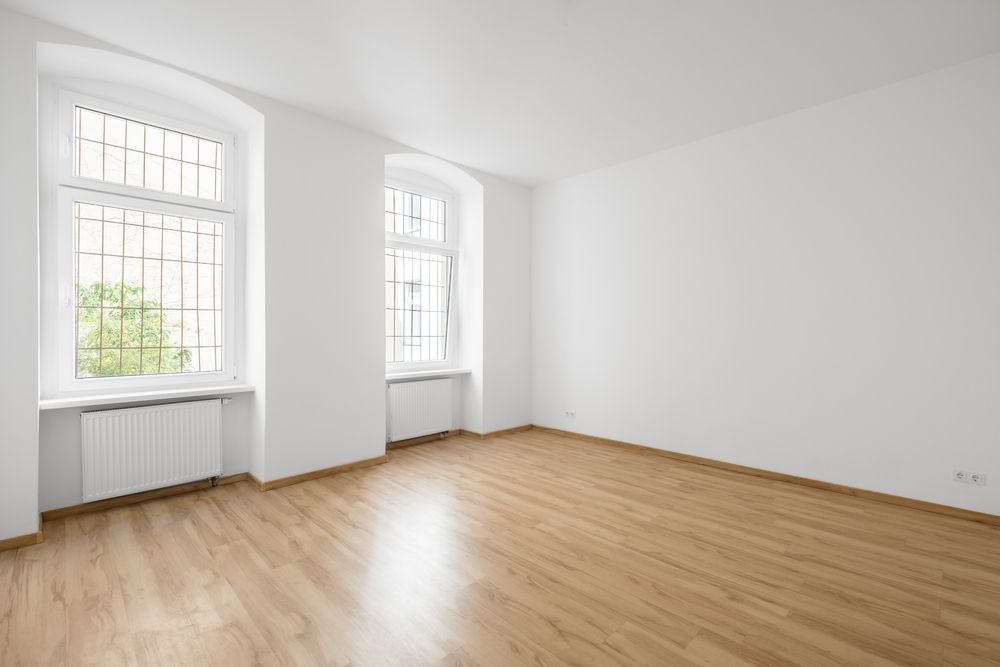 An Empty Living Room With Hardwood Floors And White Walls — Mid Coast Flooring & Blinds In Wingham, NSW