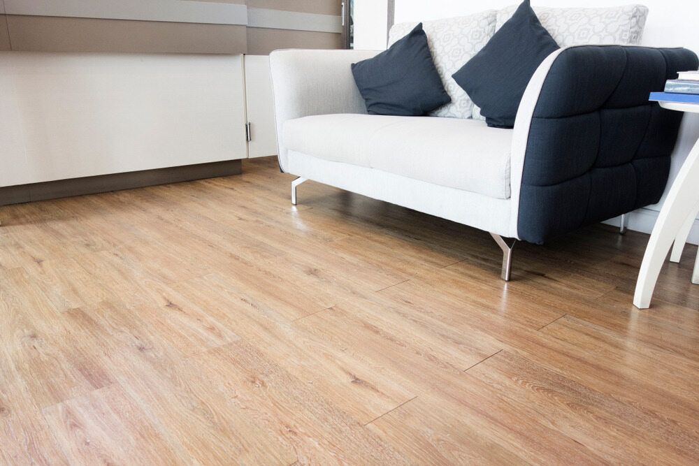 A Living Room With a White Couch and a Wooden Floor — Mid Coast Flooring & Blinds In Taree, NSW