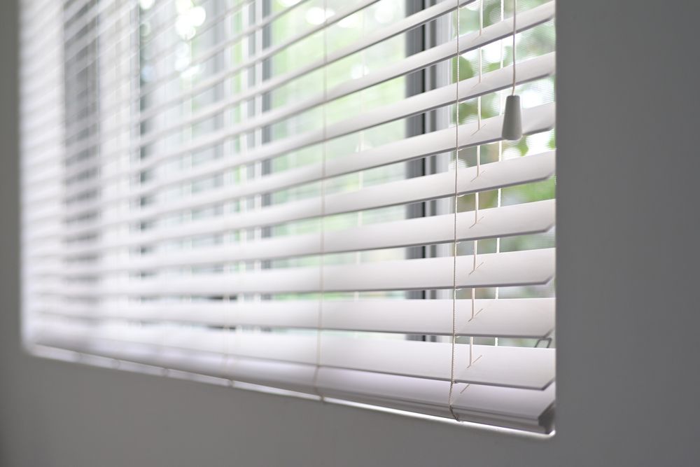 A Close Up of a Window With White Blinds on It — Mid Coast Flooring & Blinds In Taree, NSW