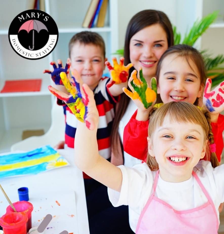 Teacher and children smiling with colorful painted hands in an art classroom