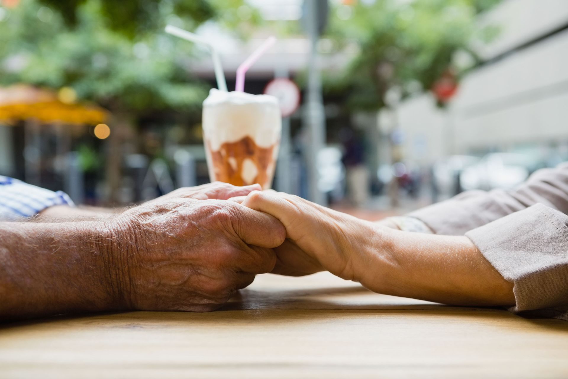 Older couple on romantic date holding hands across dinner table showing intergenerational relationships