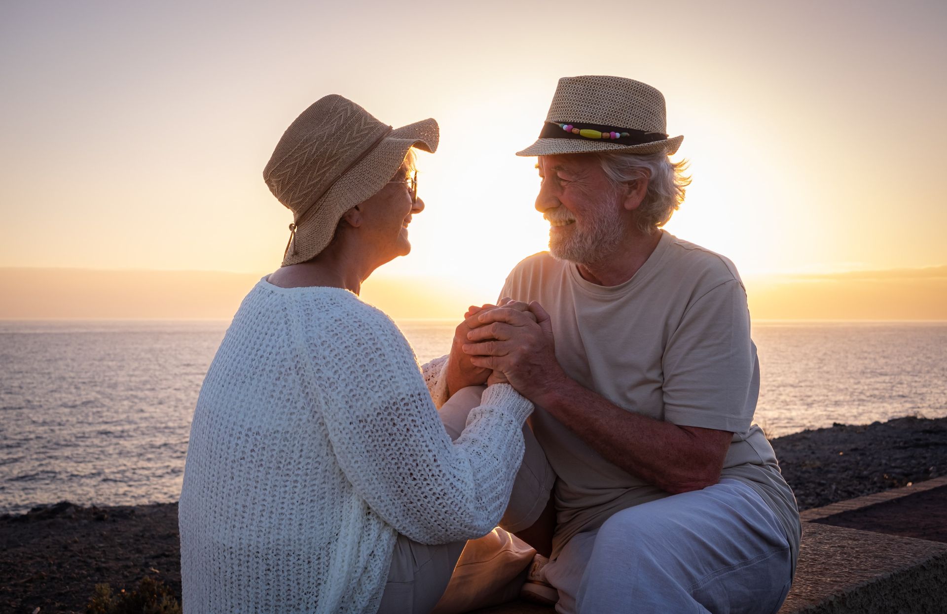 Older couple at beach during sunset holding hands showing modern relationships and age gap acceptance