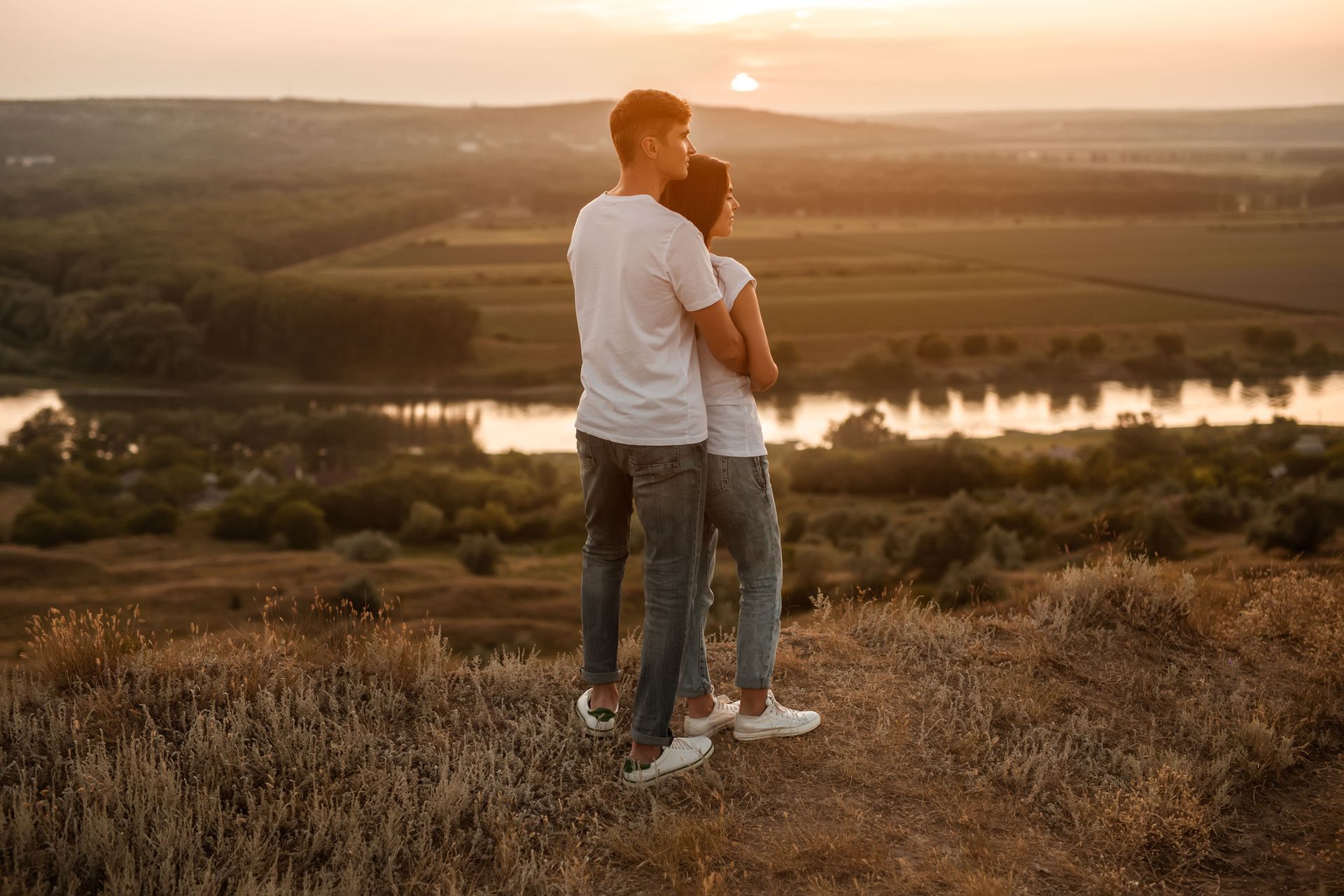 Couple hugging while looking at sunset on hill representing shared values and emotional alignment in relationships