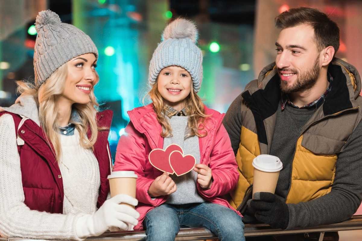 Couple with child holding paper hearts representing family-focused dating and single parent relationships