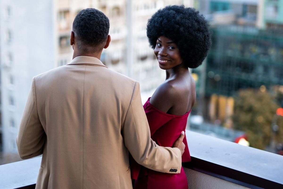 Man and woman standing and hugging, woman smiling at camera representing confidence building and successful dating outcomes
