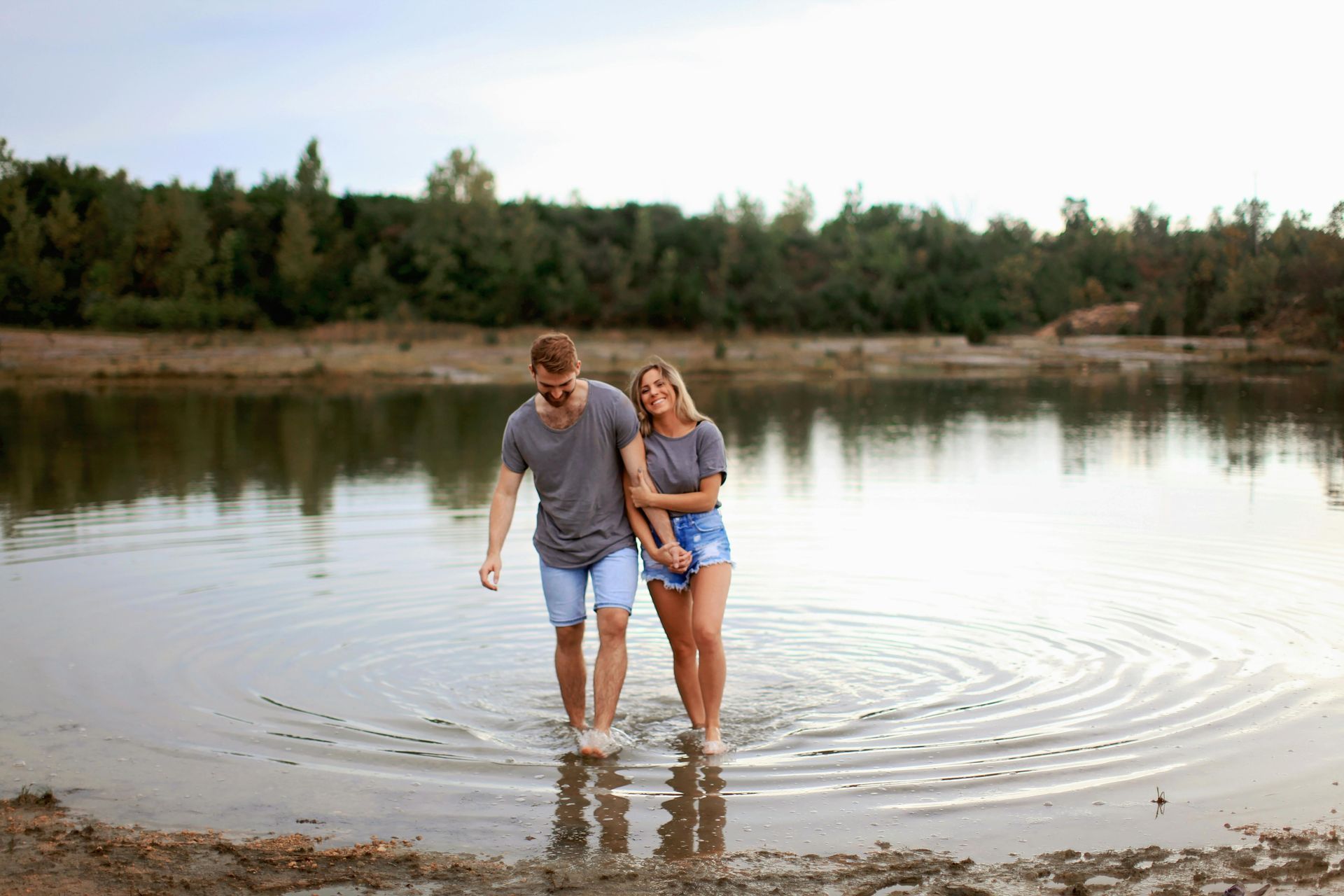 Happy couple walking hand-in-hand along a lake, symbolizing connection and harmony.