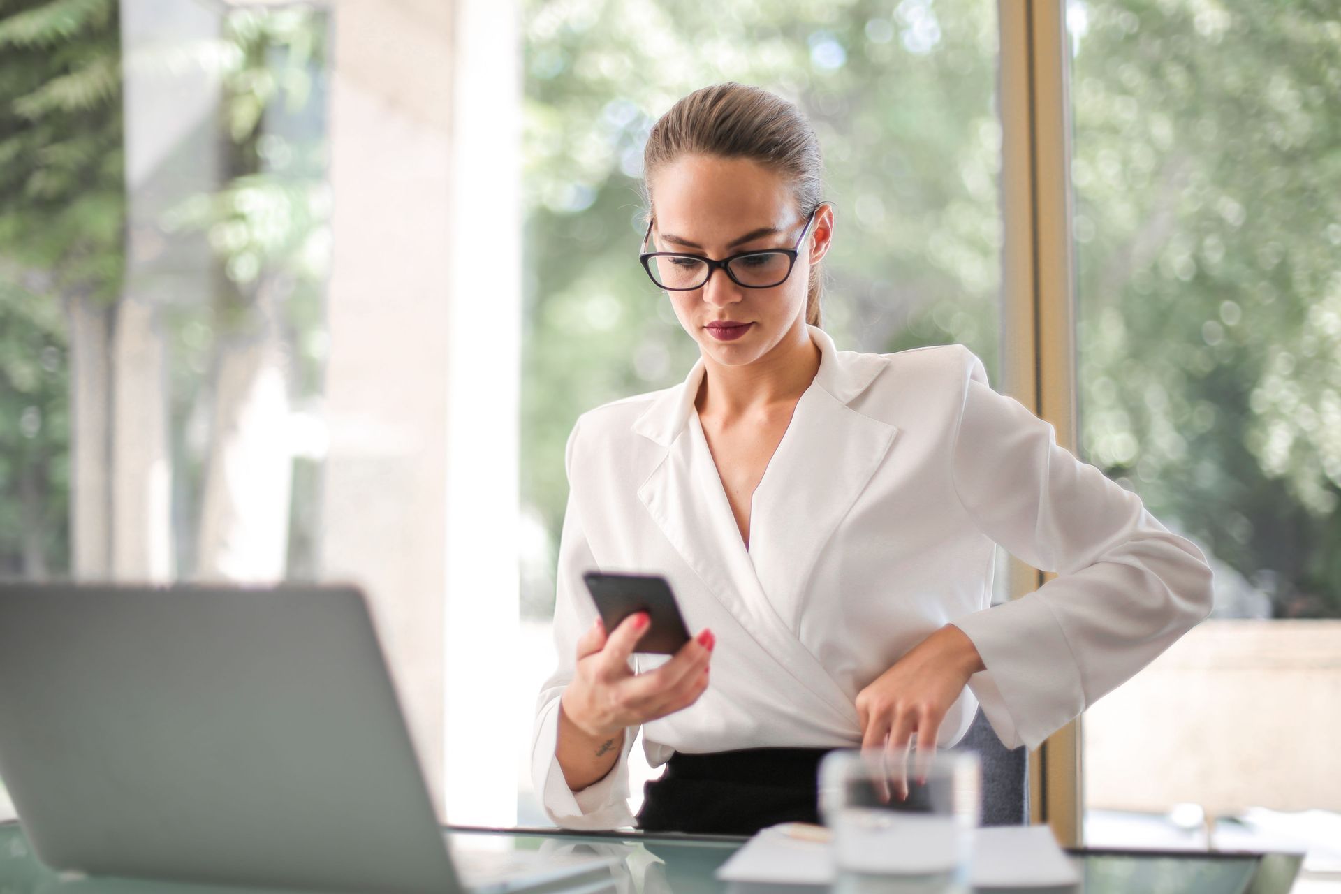 Executive reviewing phone at a modern desk, weighing dating apps against professional matchmaking