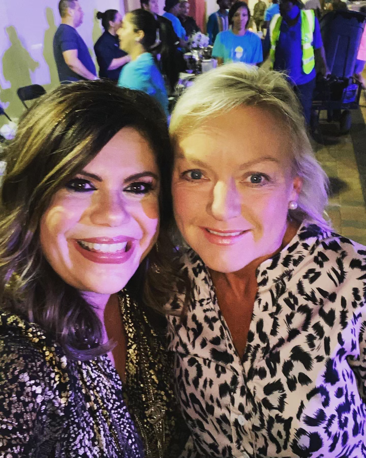 Two women are posing for a picture together and smiling for the camera.