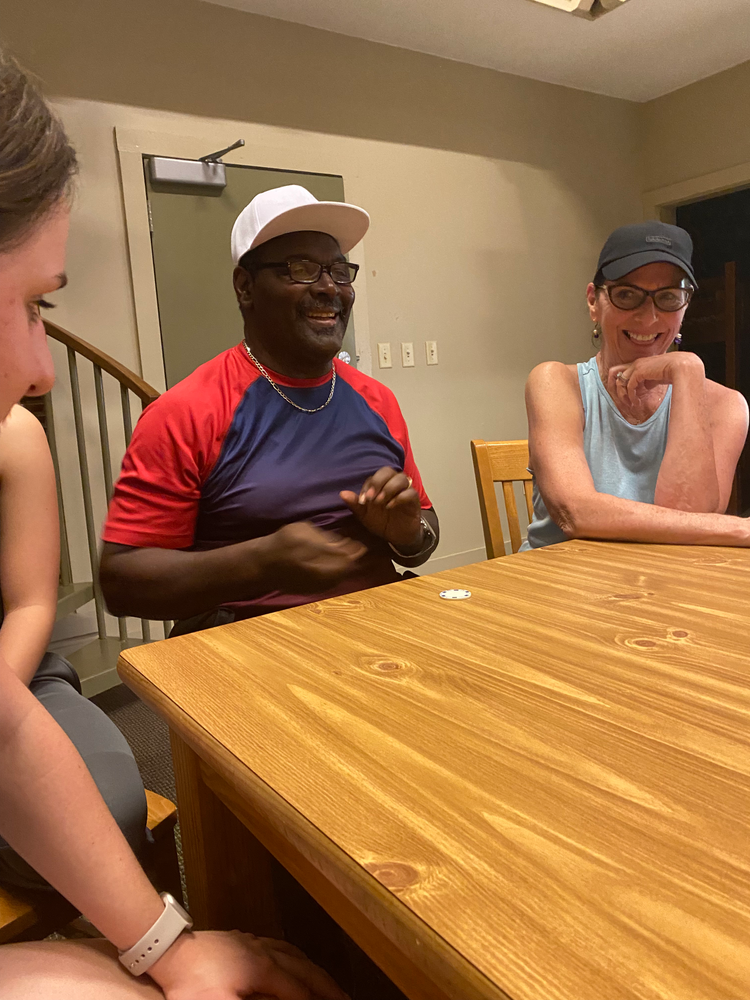 A group of people are sitting around a wooden table.