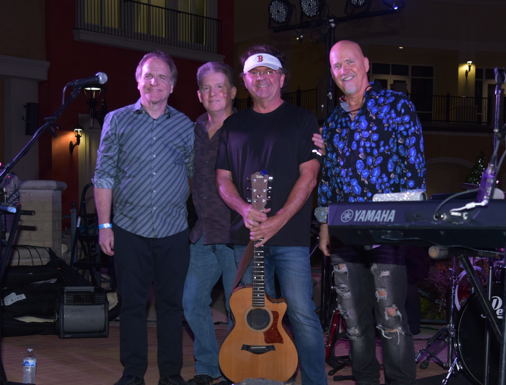 A group of men standing next to each other holding a guitar and a keyboard.