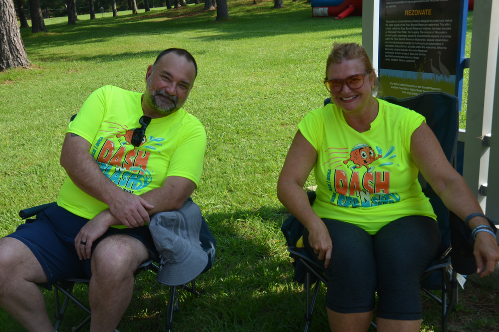 A man and a woman are sitting in chairs in the grass.