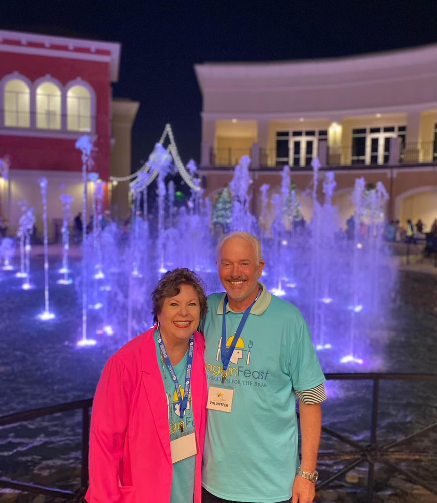 A man and a woman are posing for a picture in front of a fountain