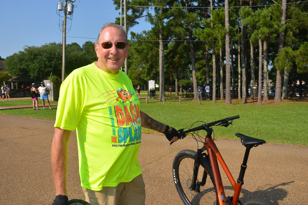 A man in a neon yellow shirt is standing next to a bicycle.