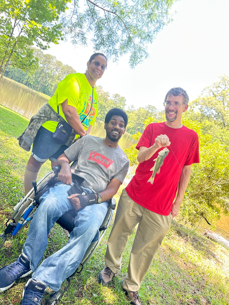 A man in a wheelchair is fishing with two other people.