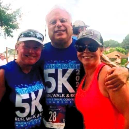 Three people posing for a picture with one wearing a 5k shirt