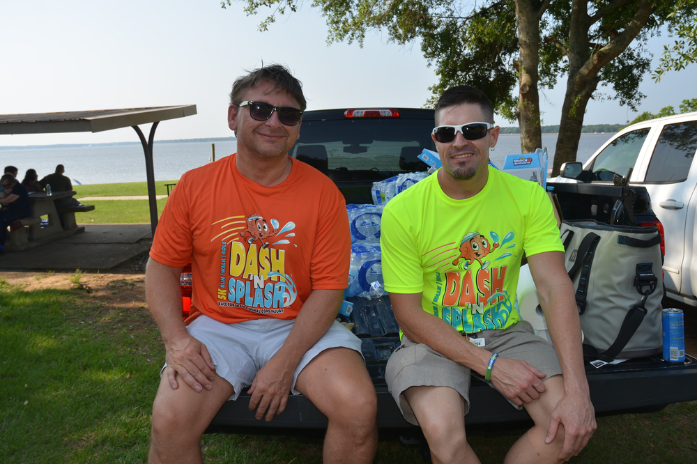 Two men are sitting on the back of a truck.