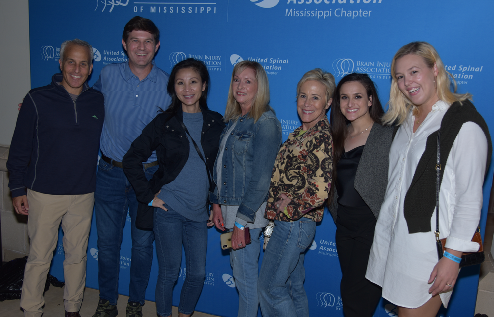 A group of people are posing for a picture in front of a blue wall.