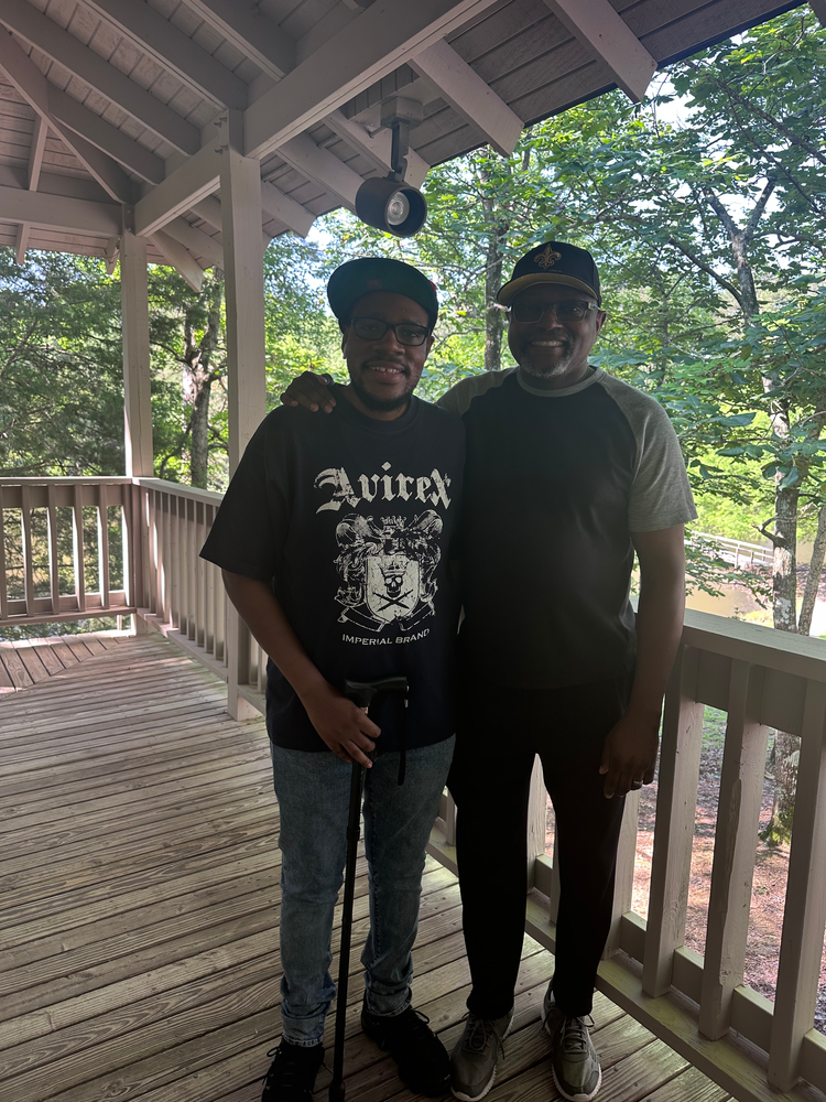 Two men are standing next to each other on a porch.