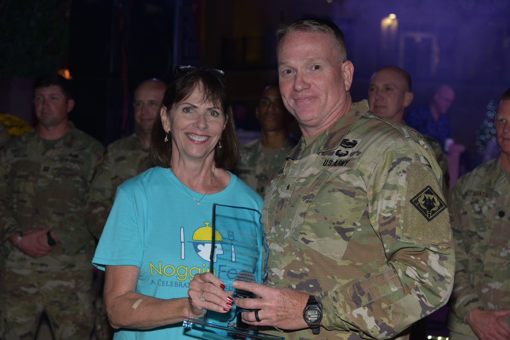 A man in a military uniform is giving a woman a trophy.