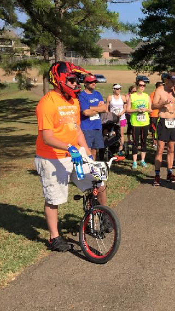 A man wearing a helmet is standing next to a bicycle.