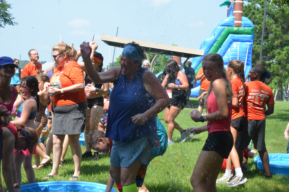 A group of people are dancing in front of a water slide.