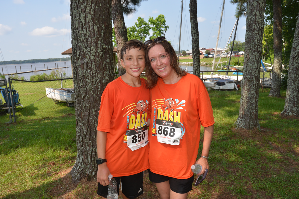 A boy and a girl wearing orange shirts are posing for a picture.