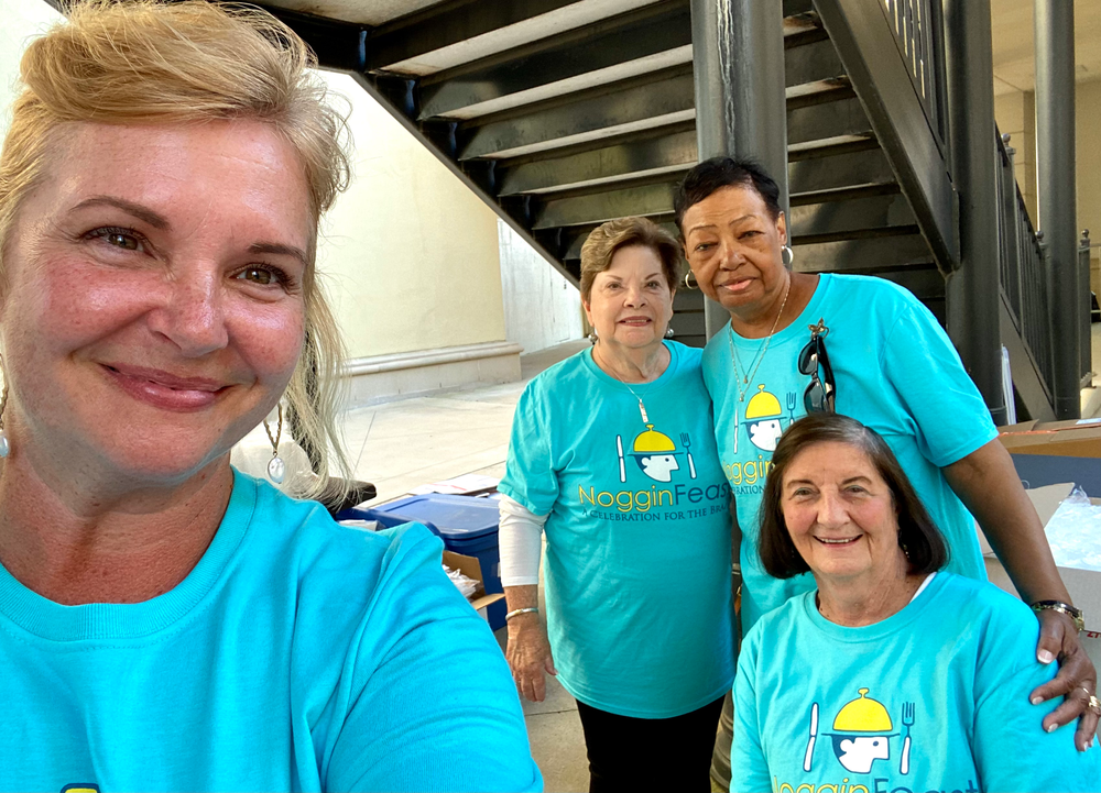 A group of women wearing blue shirts are posing for a selfie.