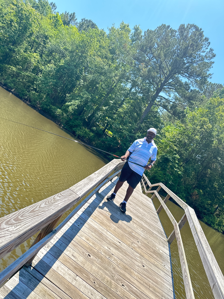 A man is standing on a wooden bridge over a body of water.