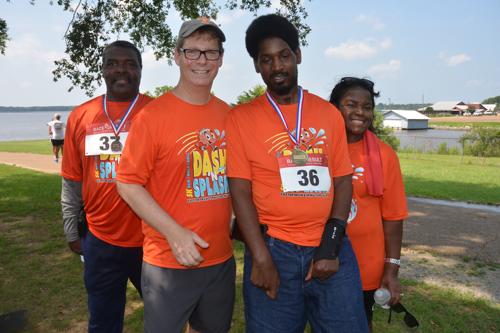 A group of people wearing orange shirts and medals are posing for a picture.