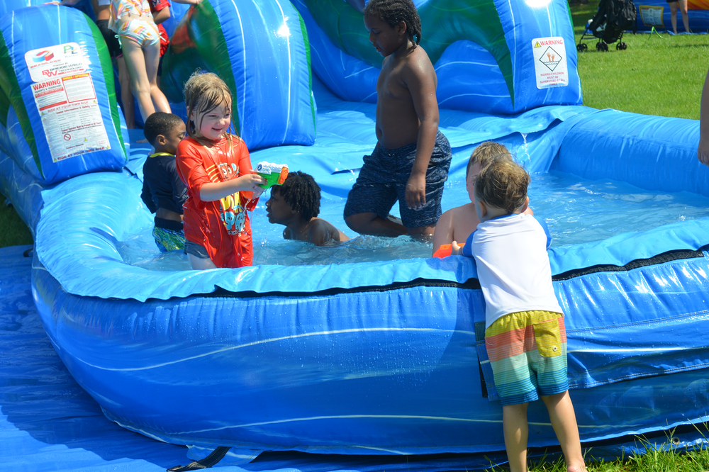 A group of children are playing on an inflatable water slide.