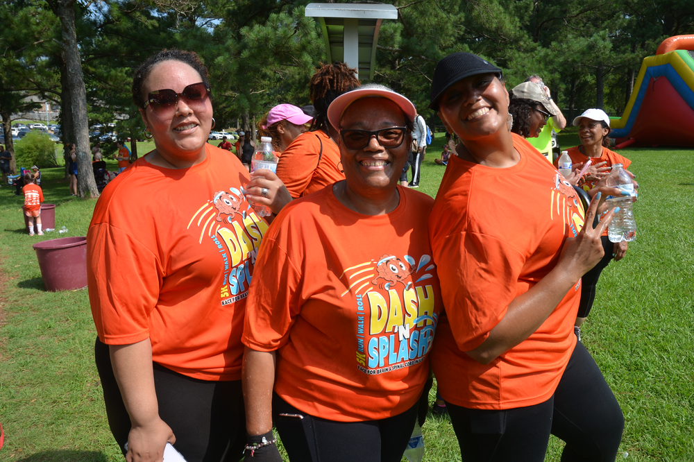Three women wearing orange dash shirts are posing for a picture