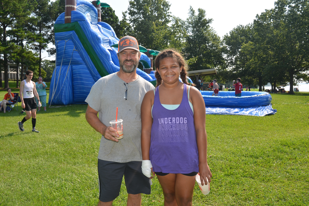 A man and a girl are posing for a picture in front of an inflatable water slide.