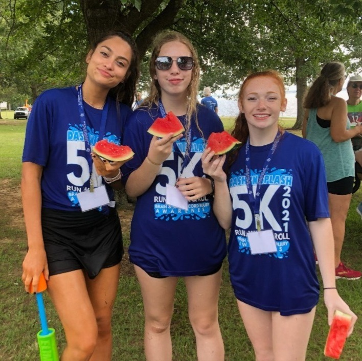 Three girls wearing 5k shirts are holding watermelons
