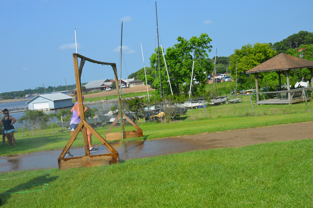 A person is standing in a muddy field next to a wooden structure.