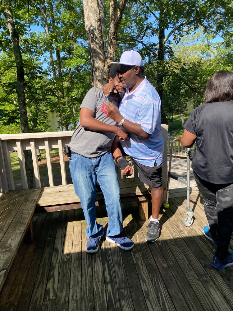 Two men are standing on a wooden deck talking to each other.