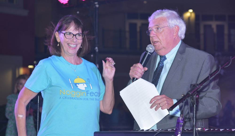 A man and a woman are standing next to each other in front of a microphone.