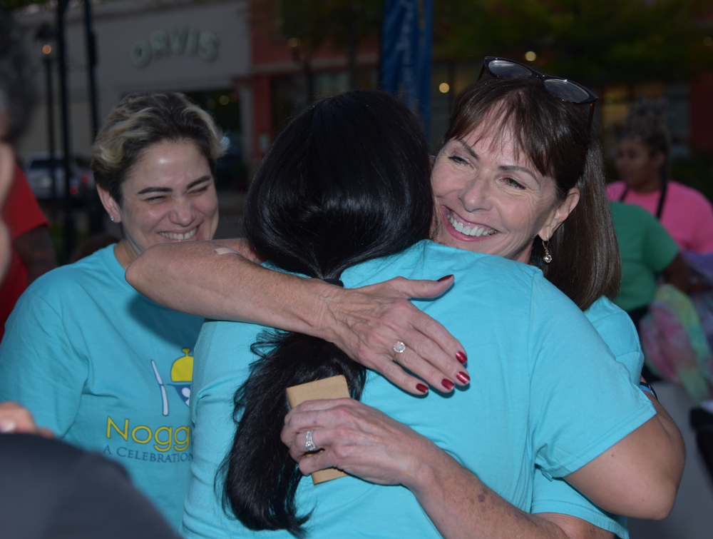 A woman in a blue shirt is hugging another woman
