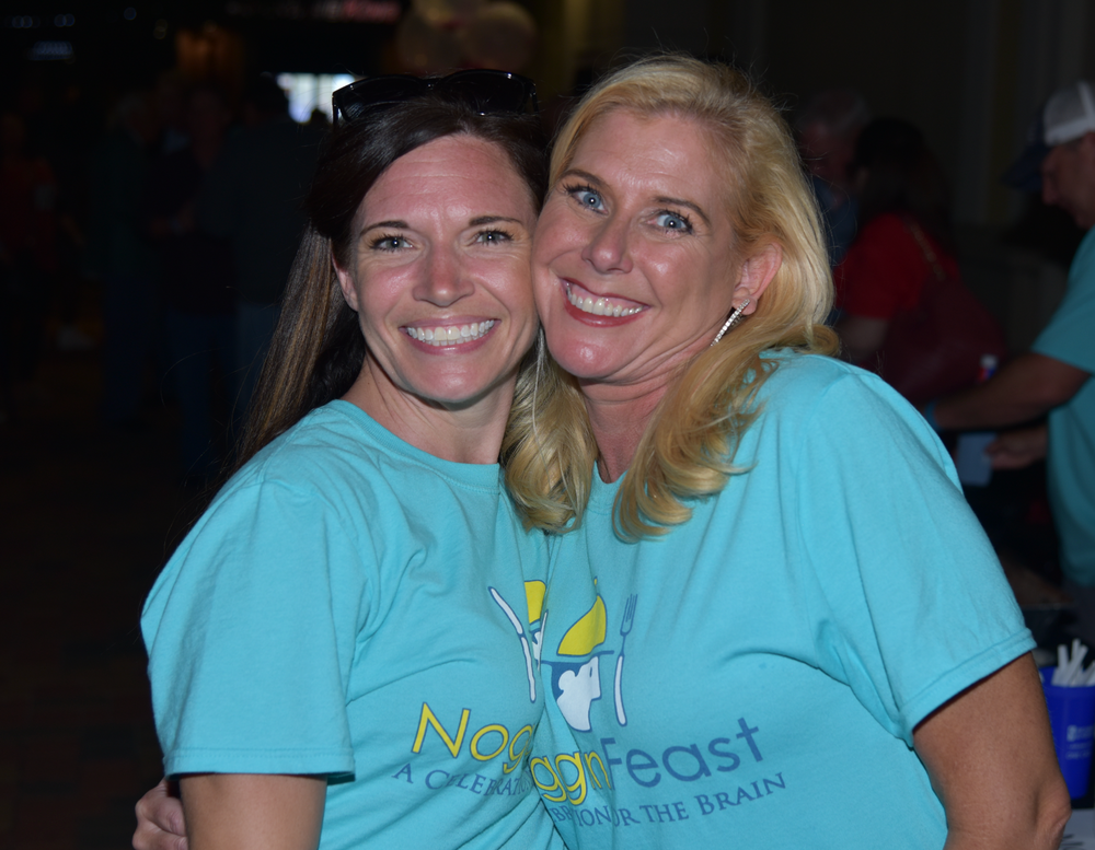 Two women wearing blue shirts that say no to feast are posing for a picture.