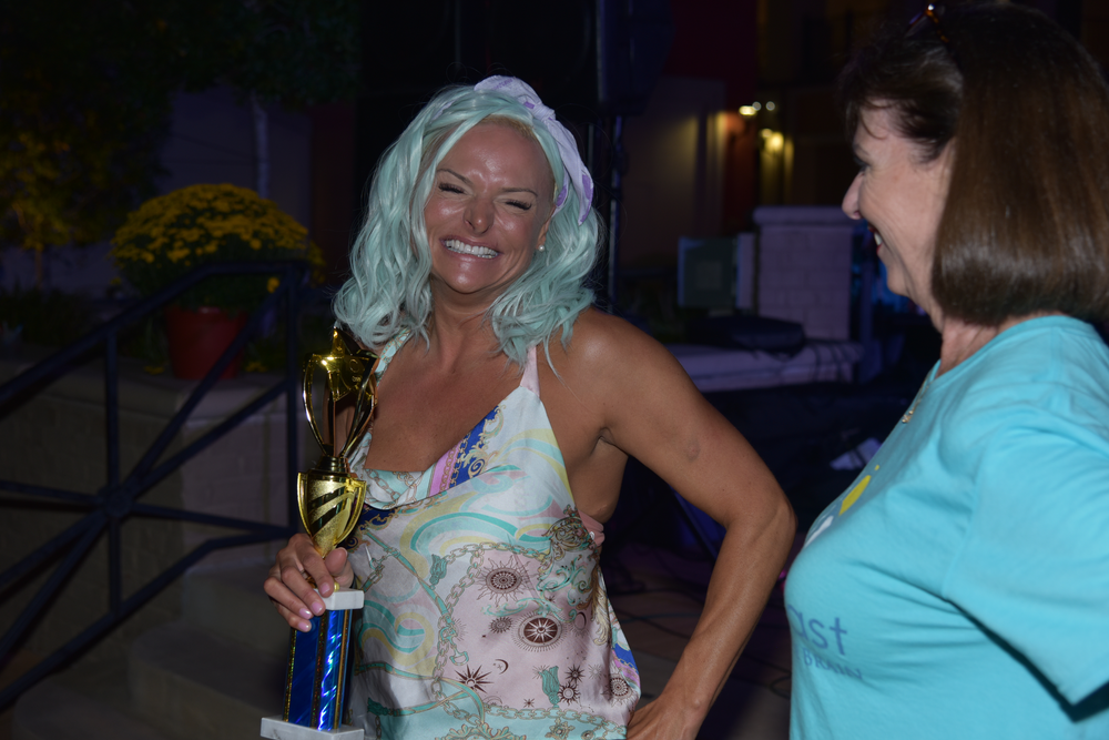 Two women are standing next to each other and one of them is holding a trophy.