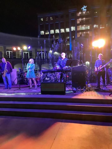 A group of people are playing instruments on a stage at night.