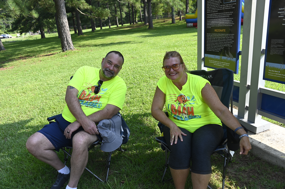 A man and a woman are sitting in chairs in a park.