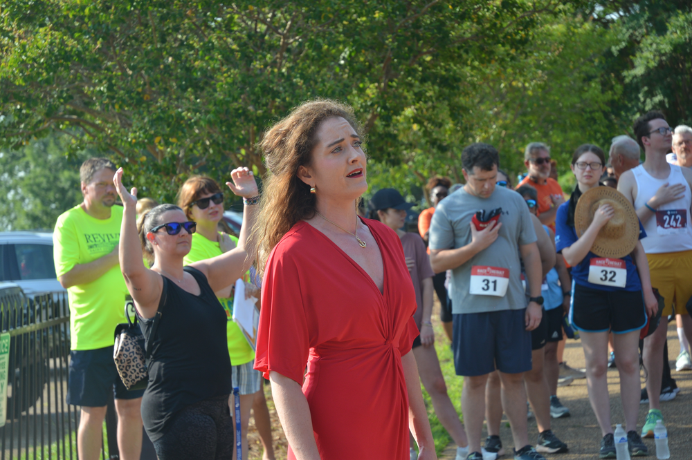 A woman in a red dress is standing in front of a crowd of people.