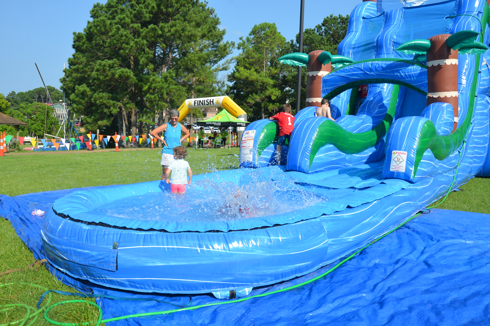A group of children are playing in a large inflatable water slide.