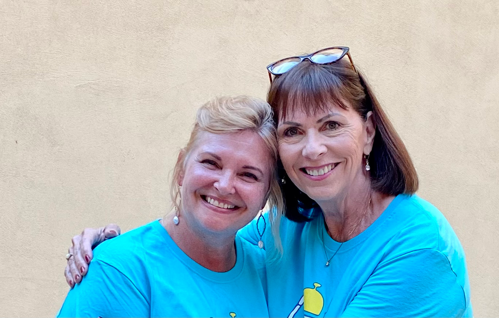Two women wearing blue shirts are posing for a picture.