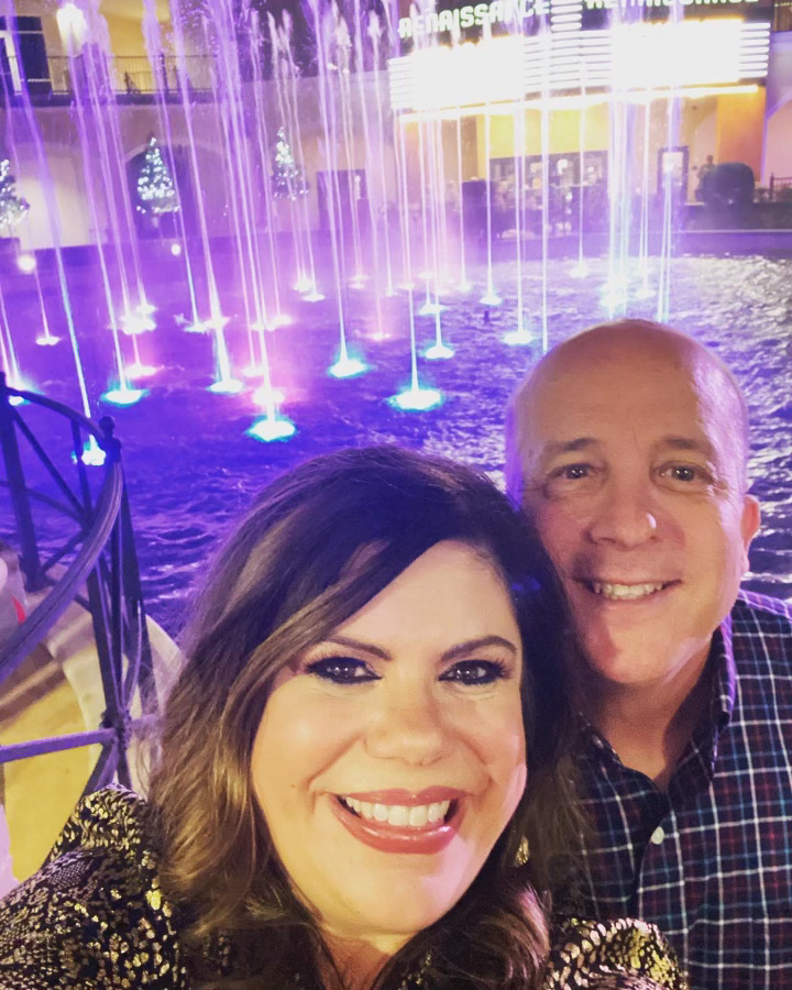 A man and a woman are posing for a picture in front of a fountain.